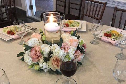 Table featuring square plates, textured linens, floating candle centerpieces with gorgeous flowers