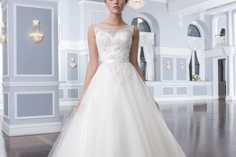 Style 6294
This strapless neckline is asymmetrically draped in charmeuse with an inverted basque waistline that sits atop a circular cut skirt. The gown has charmeuse buttons covering the back zipper and lead into a chapel length train.