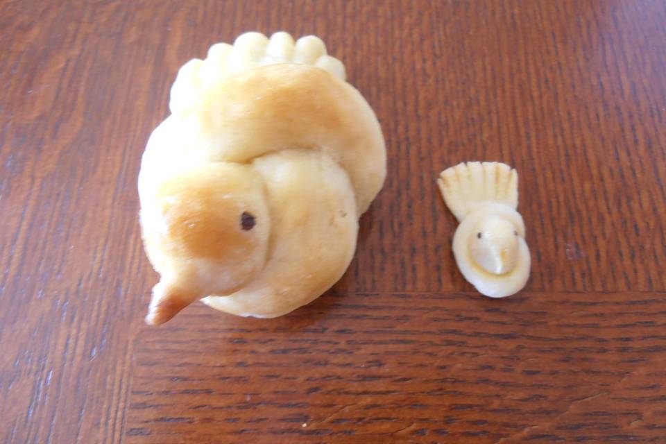 An edible bird bun next to a decorative dough bird.