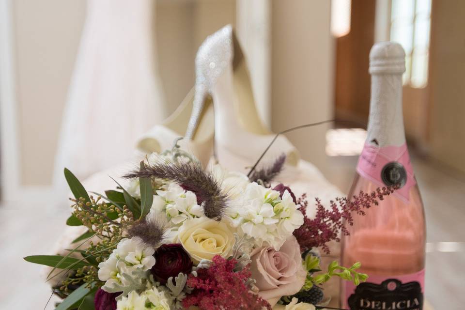 Bridal bouquet and shoes with a bottle of wine