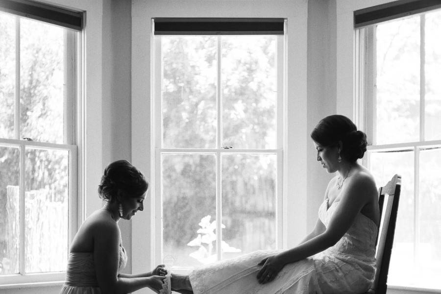 Bridesmaid helping bride with shoe