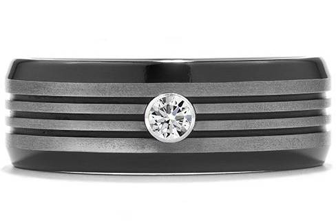 COMMANDING BLACK TITANIUM MULTI-GROOVE BEVEL BANDComposed of classic black titanium, with the added design element of a single, perfectly cut diamond, this stately men’s band has a bold, masculine look. With multiple bevels in the center, this ring has a truly unique, yet comfortable, design.