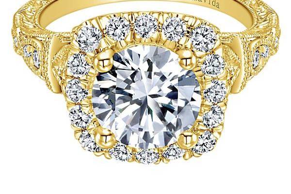 GABRIEL & CODULCEA delicate design is accentuated with pave diamonds along the band leading into a diamond halo center stone in this 18K yellow gold Amavida engagement ring