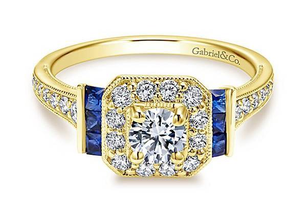 GABRIEL & COSYLVIAA Victorian styled engagement ring that perfectly accents our halo with six sophisticated side sapphire stones. The polished band is filled with diamond channels that lead to scrollwork underneath your center stone.
