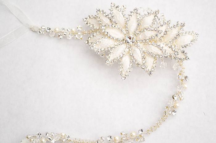 A white enameled lily flower blooms on a delicate crystal, pearl and rhinestone chain and is traced with lustrous rhinestones. May be worn as a bridal headpiece or wedding belt.