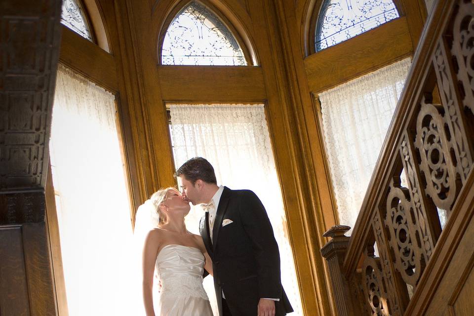 Newlyweds kiss by the staircase