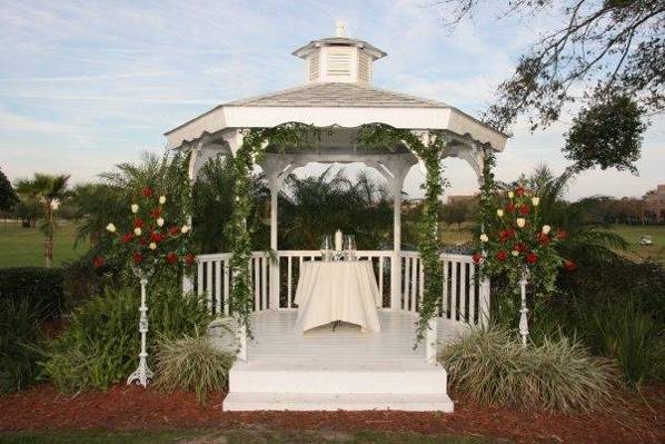 Heathrow Country Club Gazebo decorated with hanging Ivy and tall florals in white stands made with red roses and french tulips.