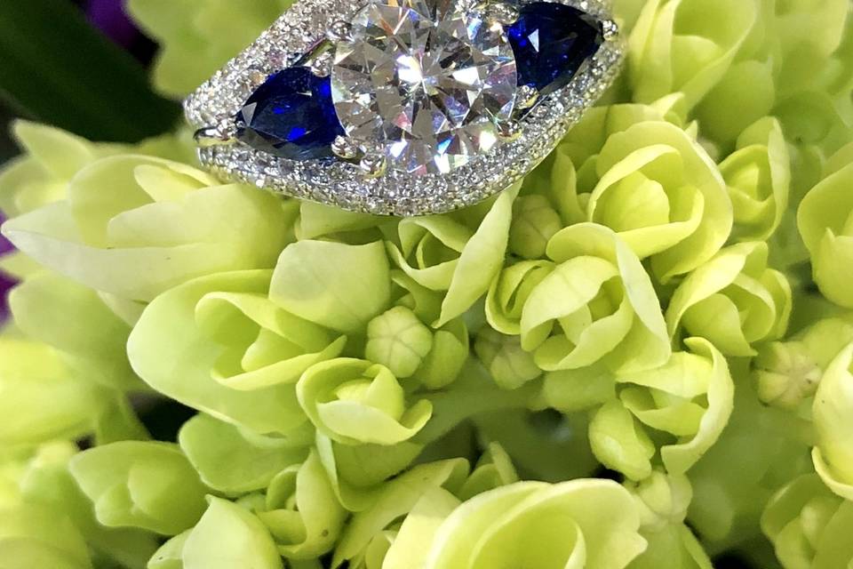 This elegant Simon G. 18K white gold engagement ring shimmers with .1.16 total carats of pear cut sapphires and .45 total carats of round cut diamonds in a stunning design. Diamonds are F/G in color and VS in clarity. The mounting is designed to hold a 7.5mm center stone (approximately 1.5 carats) - sold separately.All Simon G. products are made of 18K gold or platinum, are hand made, and all stones are hand set. Each piece undergoes eight to 10 quality checks before leaving the Simon G. factory, depending on the complexity of the piece.