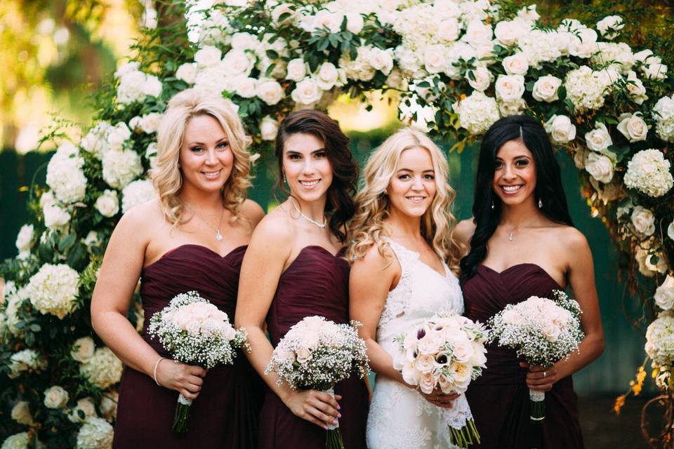 Bride and bridesmaids by the floral arch
