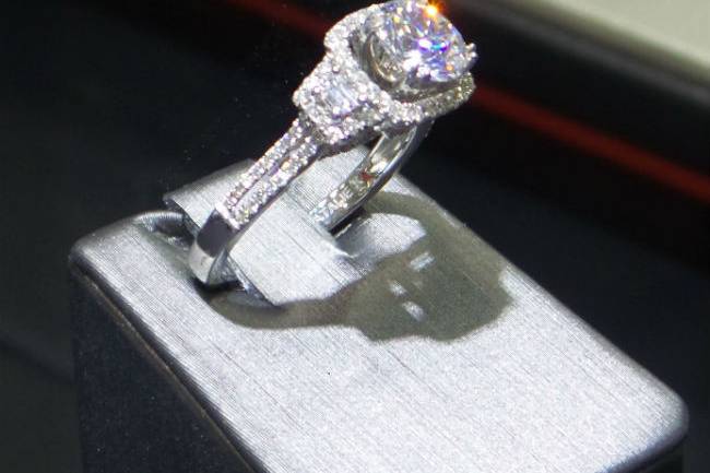 Trapezoid side stones, a split shank and a diamond halo are the unique features of this glamorus Natalie K designer ring.
18k White Gold