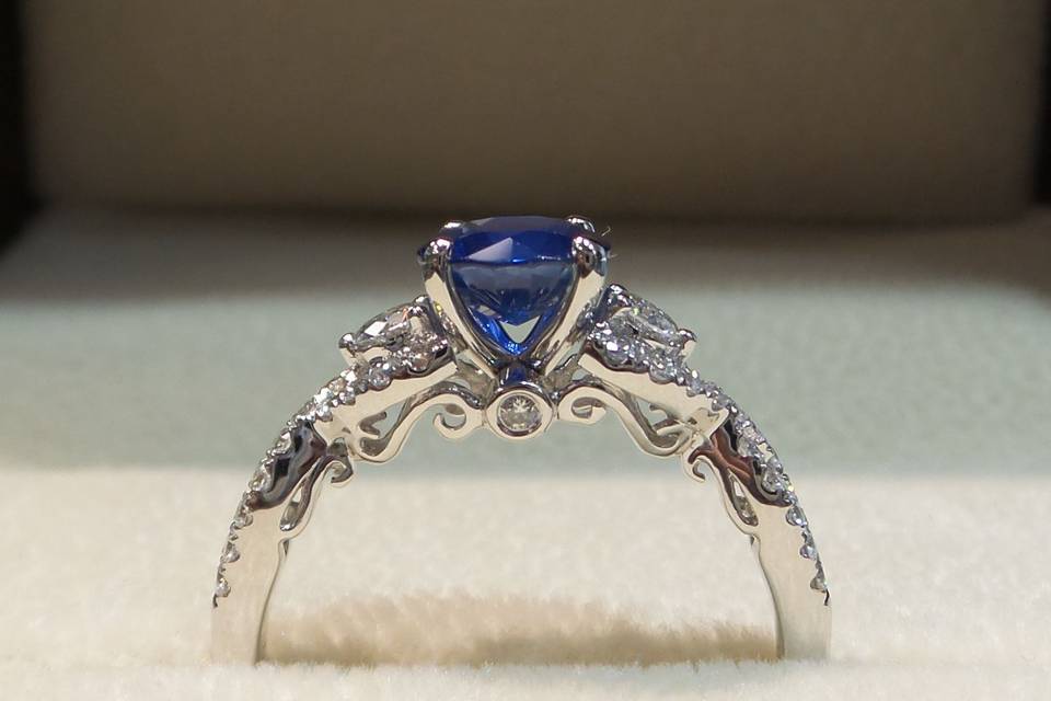 This vintage inspired design features delicate scrollwork, classic round side stones and a brilliant round cut sapphire center. Customize any engagment ring with the center of your choice.
18k White Gold