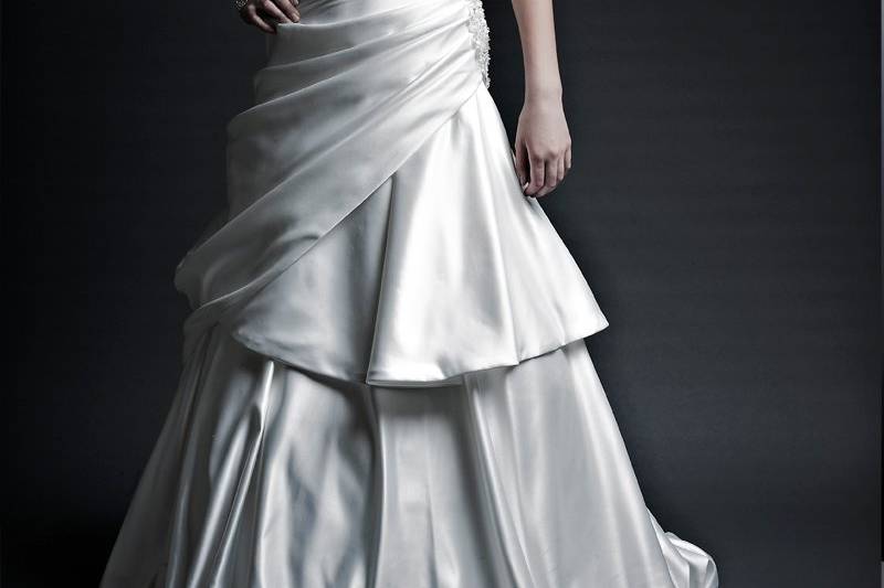 DelilahItalian Satin. Dropped waist modified A-Line gown. Straplesssweetheart neckline with pleated bodice. Draped skirt with bubble hem line.  Accented with beaded applique at side waist swwet.