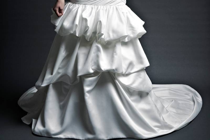 PamRegal Satin. Droped waist Aline gown.  Strapless caught up gown with asymmetrically pleated fabric across the bodice.  Bustles add luxurious volume to gathered Aline skirt.