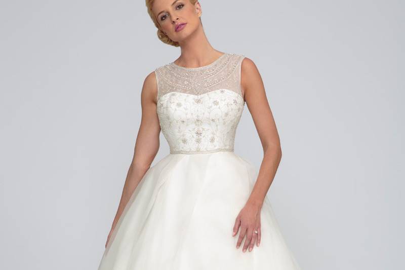 Caroline  Silk Organza.  Natural waist gown with full flowing asymmetric pleated skirt and cathedral length train.  Organza beaded illusion neckline and bodice with covered buttons.