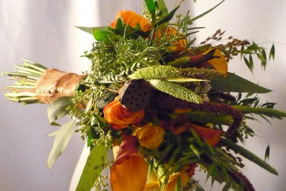 A great fall collection--multiple grasses, burnt orange mini callas and lotus pods wrapped with burlap ribbon.