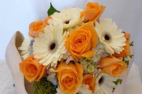 A winning combination of Orange Unique roses, light blue hydrangea and Grizzly white mini gerbs, along with a bit of brezzilia.