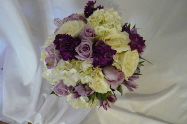 Vibrant colors combine in this bouquet! White mini callas, Circus roses, purple lisianthus, Maine Blue limonium, and italian ruscus greens