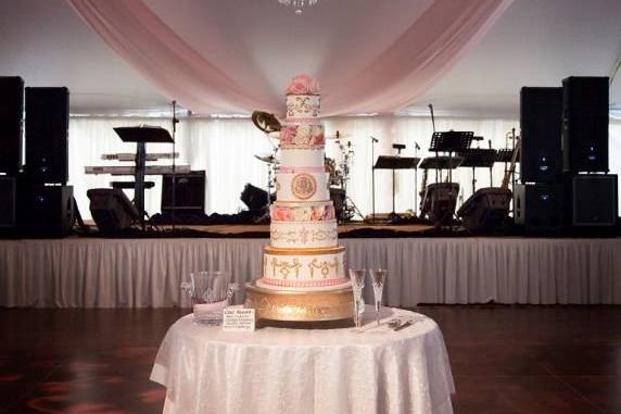 Their beautiful wedding cake with the chandelier in the background.