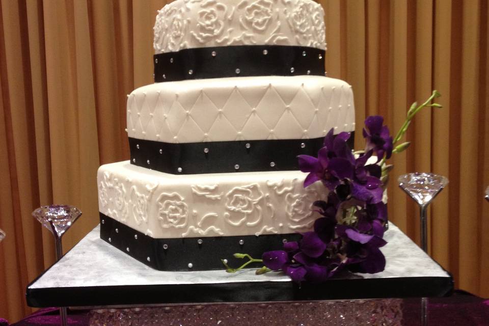 Wedding cake with black ribbon and purple flowers