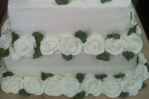 Square cake with buttercream roses bordering base of each layer.