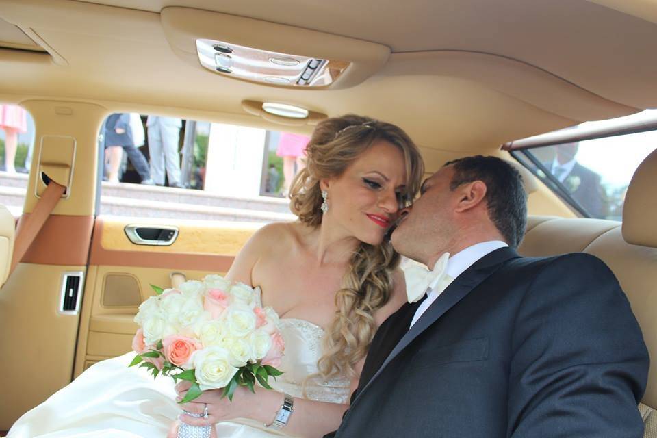 The groom kissing his bride while riding the Bentley
