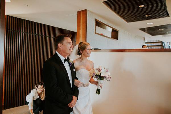 Kim adjusting the bride's train as she walks down the aisle