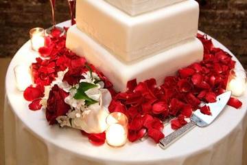 Square tiers covered with fondant and a satin ribbon at the base of each tier.  Red roses on top tier and petals all around on the table