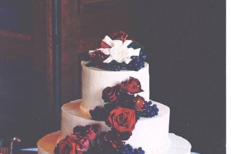 Round tiers covered with fresh grapes and roses frosted smooth with buttercream