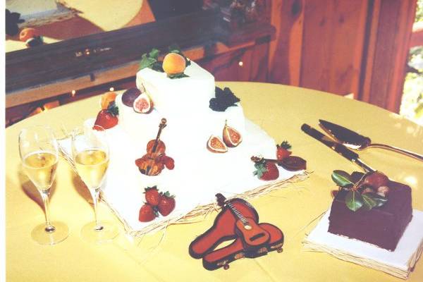 Square tiers frosted rough with fresh fruit and musical instruments.
Chocolate devils food grooms cake covered with ganache
