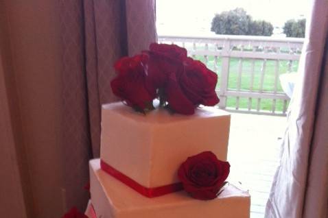 3 square tiers offsetting one another.  Deep red roses and red ribbon at each edge.  Cupcakes as well