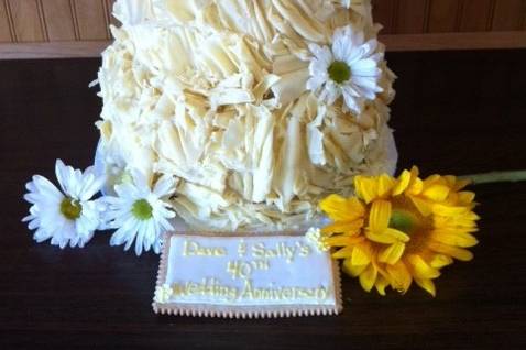 Country themed cake.  3 round tiers covered with white chocolate shavings, white and yellow daisies and sunflowers