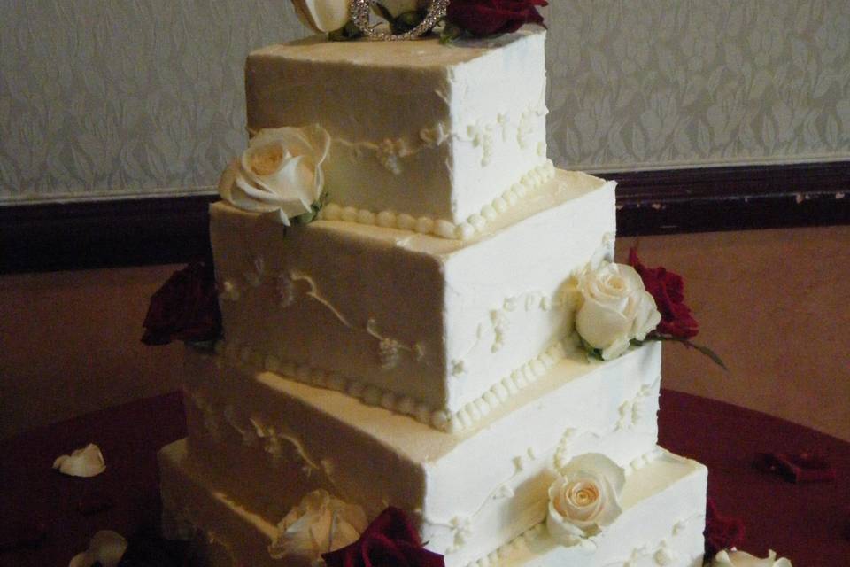 4 square cakes offsetting one another.  Piped with grape and vine pattern.  White and black magic roses with a silver 