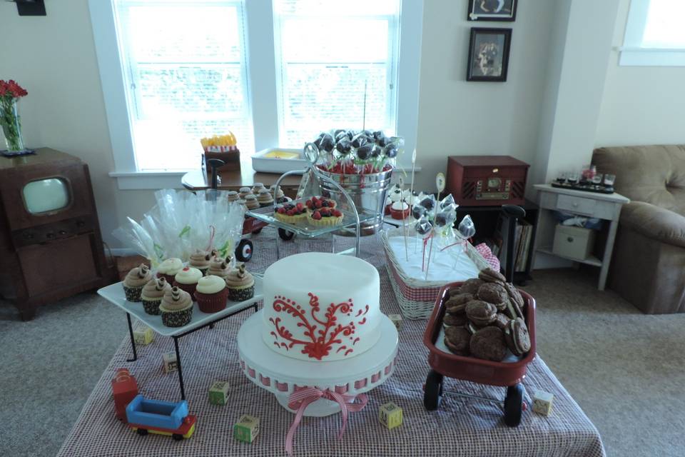 Country fair themed dessert bar.  Fondant cake with red scroll work, assorted cupcakes, filled brownie bites,