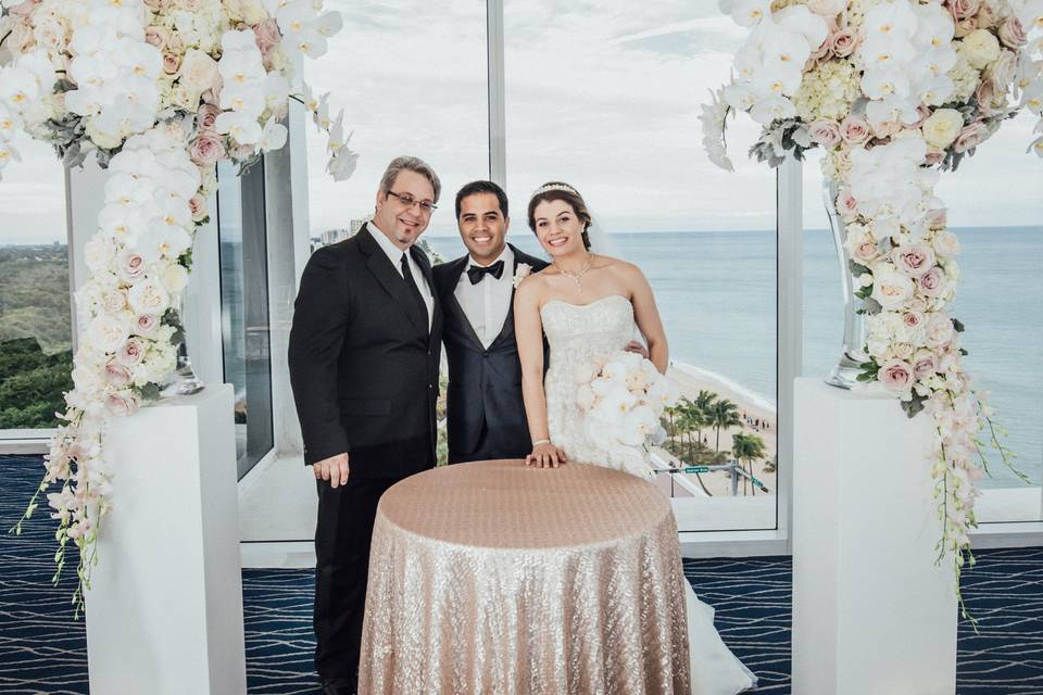 Officiant and newlyweds by the arch