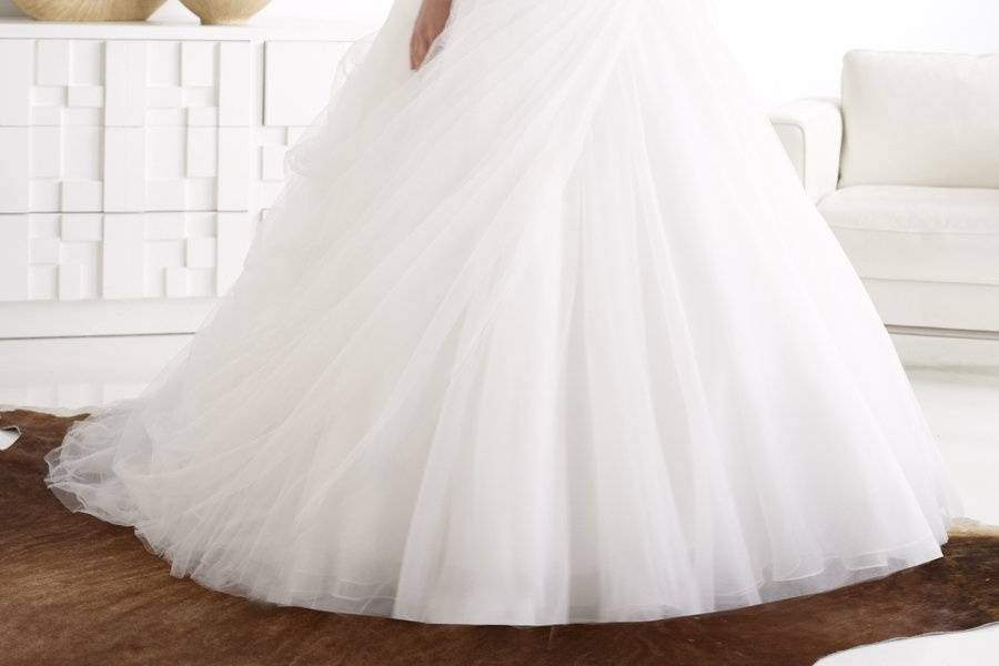 Style H1212This tulle ball gown features soft draping to one side and finished with feathers and a handmade rosette. Bodice features lace and accented with Swarovski crystals and beading. Finished with a zipper closure.