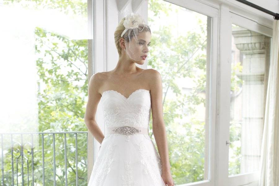 Style H1218This tulle A-line features a ruffled organza bodice. Lace is placed delicately throughout and finished with a beaded sash.