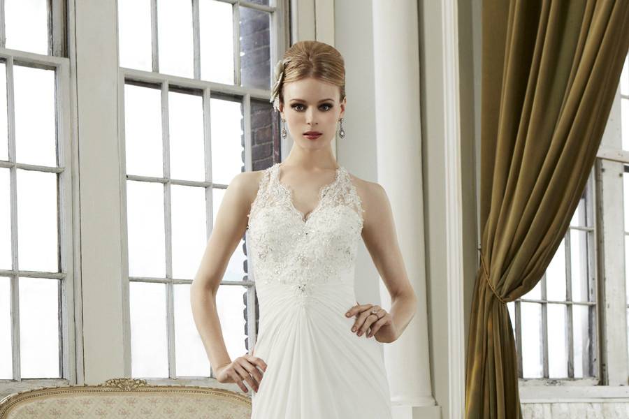 J 6274Fall 2013A trumpet lace gown with a sculpted neckline, featuring scalloped lace along the halter V-neck and racer back. Buttons run down the sheer lace back and a zipper closure finishes the look.