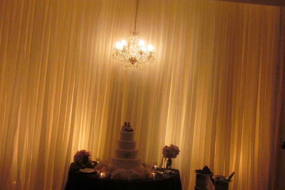 Gathered draping and up lighting and a gentle glow from our crystal chandelier are a perfect backdrop for the brides cake