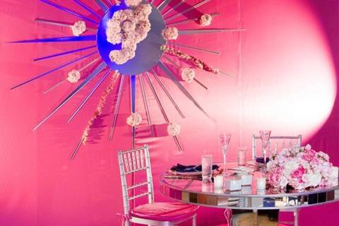 Our bride and grooms special mirrored table in front of a mirrored starburst with floral monogram on hot pink satin background