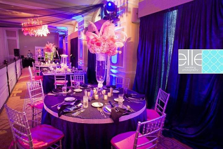 Tall crystal banded vases filled with hydrangea roses and peonies and a gathering of ostrich plumes. The curtains were all draped in cobalt blue crush