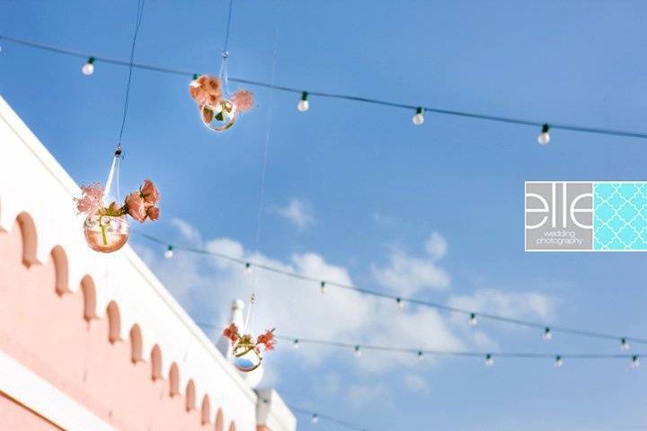 Floral glass bubbles suspended amidst a canopy of festival lights during the cocktail hour