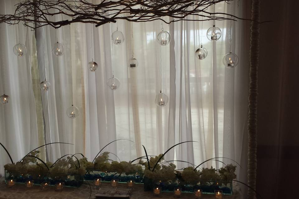 Long centerpiece with glass votive bubbles suspended from curly willow