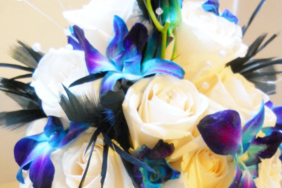 Blue orchids, white roses, black feathers and damask wrap.