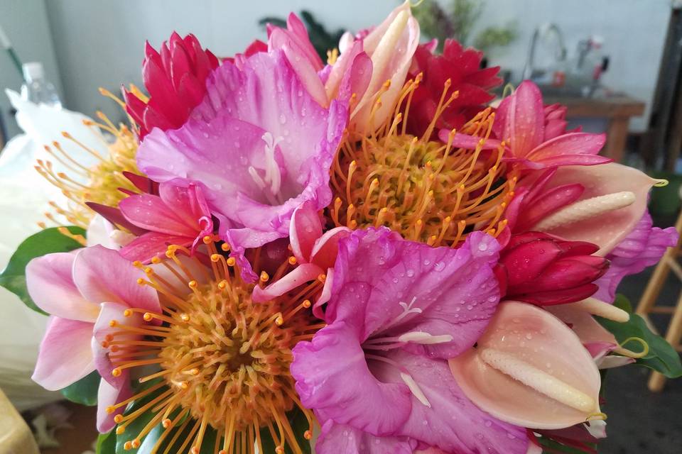 Tropical styled, hand tied bouquet designed with gladiolus, protea, anthuriums, plumeria and gingers