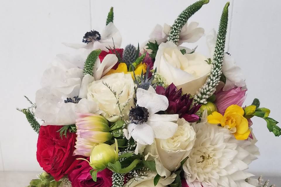 A whimsical hand tied bouquet with lots of bright spring flowers