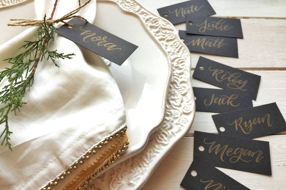 Elegant black name tags with gold calligraphy lettering.
