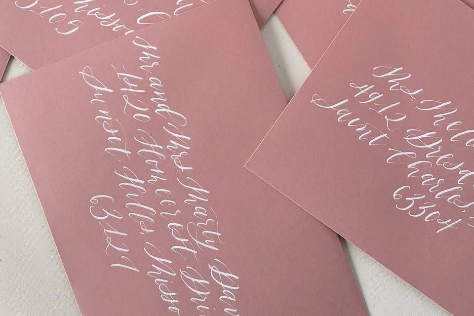 White calligraphy on dusty rose envelopes
