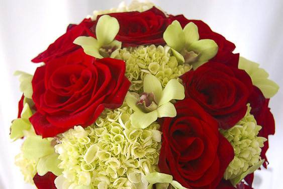 Bright red charlotte rose against a background of green orchids and green hydrangea.