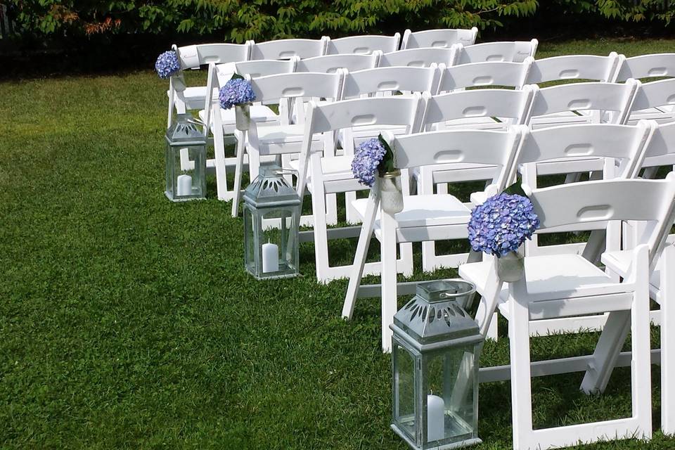 Ceremonial aisle dressed with lanterns and hanging mason jars with hydrangeas.
