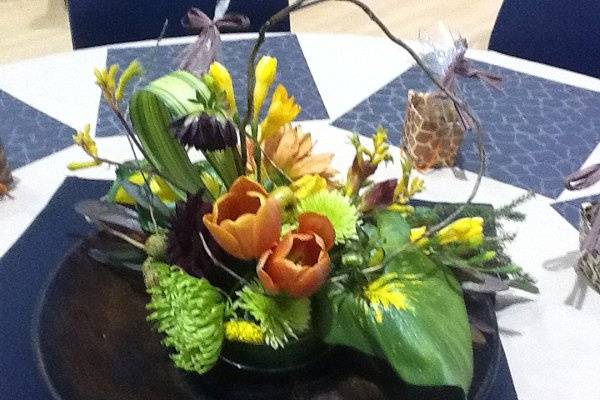 Event centerpiece of Calla foliage, orange Tulips, yellow Kangaroo paw, alstromeria, green Spider mums, and curly willow